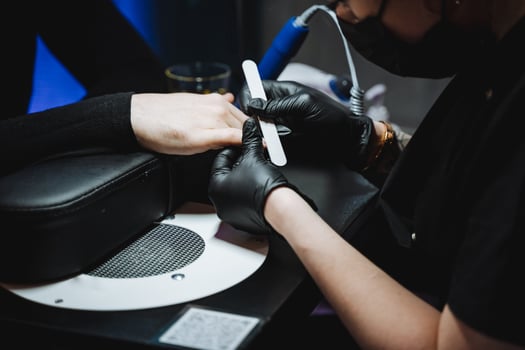 Woman in gloves doing manicure on man's hand while filing nails. photo