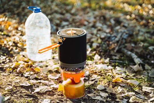 On the ground beside the stove, a bottle filled with water and a pot are resting quietly, creating a peaceful scene in the kitchen, ready for use in preparing a meal or drink photo