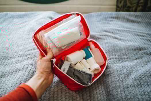 A person is carefully holding a first aid kit on a bed, ensuring that all the necessary items for personal care and emergencies are readily accessible within the kit for any potential needs photo