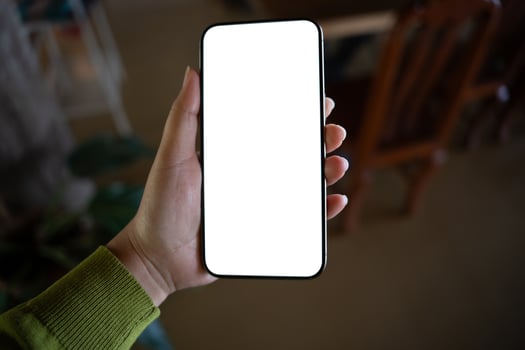 a hand holding up a blank white phone screen photo
