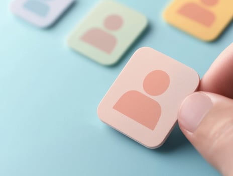 Hand holding pastel colored icon representing person, surrounded by similar icons photo