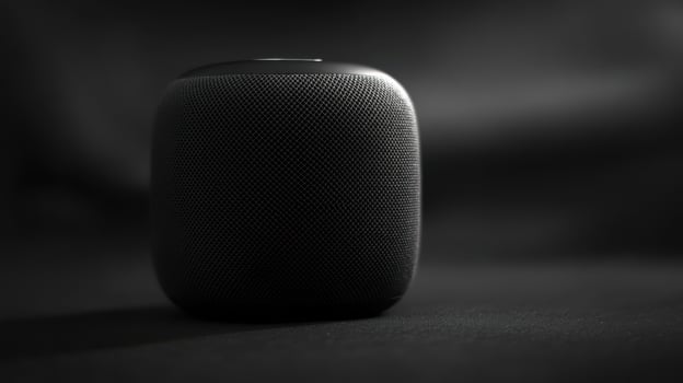 Compact black speaker on a dark surface with a soft shadow creating a sleek and modern aesthetic photo