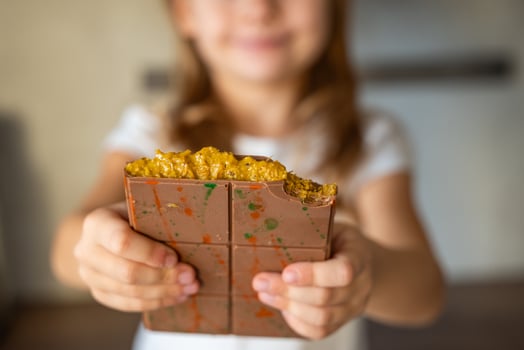 Dubai chocolate with pistachio paste and kataifi dough in hands of little girl. Confectionery handmade sweets at home in the kitchen. High quality photo
