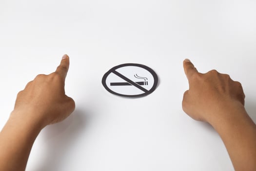 A person's hands show a warning gesture with round paper no smoking sign photo