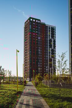 A beautifully crafted brick walkway gracefully leads visitors toward a tall and impressive building set within a wellmaintained park, inviting exploration and admiration photo