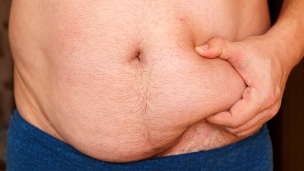A man holds his stomach with his hands shows his fat. photo