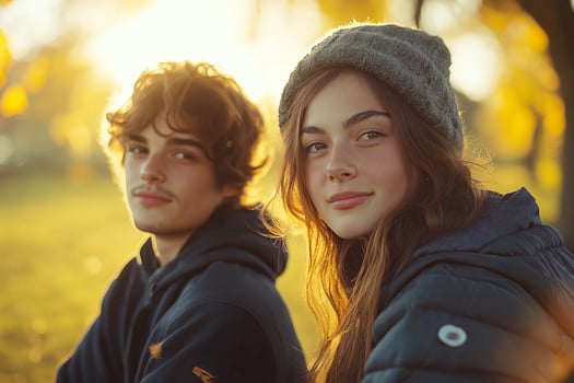 Young couple enjoys autumn sunset in a park while wearing cozy outfits and warm smiles photo
