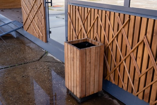 A beautifully crafted wooden trash can is positioned right next to a rustic wooden wall, blending seamlessly with its surroundings and enhancing the overall aesthetic of the space photo