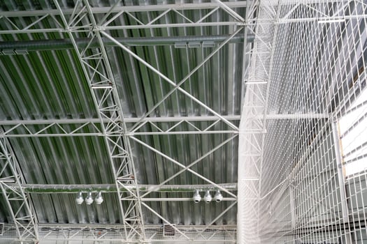 The buildings ceiling features an elaborate design with intricately arranged metal beams, providing structural support while creating a captivating aesthetic that draws attention photo