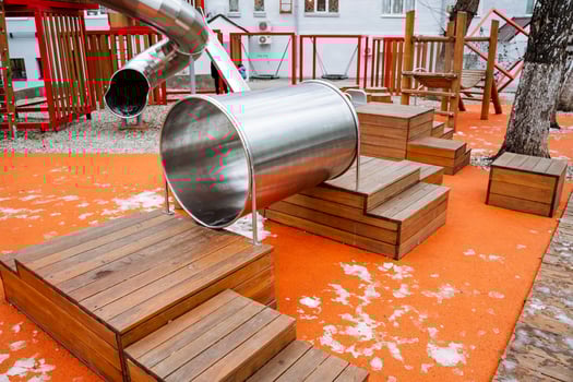 A shiny and durable stainless steel slide is gracefully going down the wooden steps located in a fun and exciting playground, inviting children to enjoy their playtime experience photo