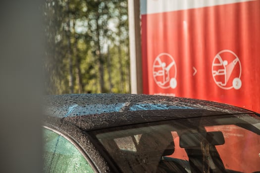 Partially Visible Car with Water Droplets and Red Instructional Sign photo