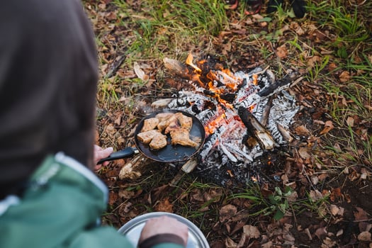 Savor the joy of outdoor cooking over a campfire while grilling delicious meat, surrounded by natures stunning beauty alongside friends and family photo