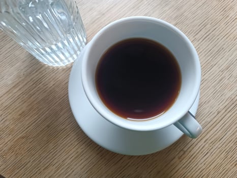 Top view white cup black coffee with water bottle wooden table. Morning routine coffee breakfast photo