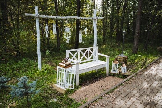 A beautiful white bench is sitting gracefully in the very middle of a serene forest, surrounded by lush greenery and tall trees, creating a peaceful and inviting atmosphere photo