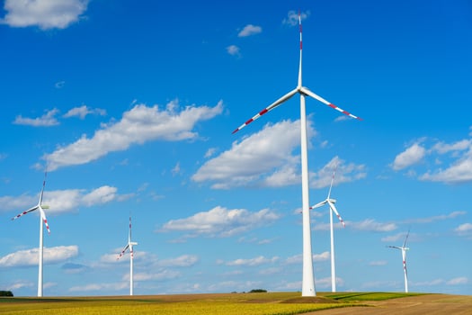 Wind turbines generating clean energy in a rural field under a blue sky with white clouds photo