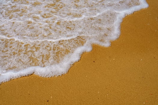 Soft Wave of the Sea Gently Lapping on the Sandy Beach Under the Bright Blue Sky photo