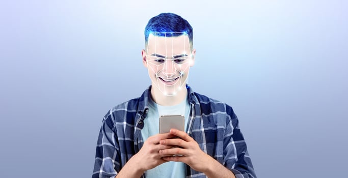 A young person engages with their smartphone, showcasing facial recognition technology. The modern backdrop emphasizes the advancement of identification methods in daily life. photo