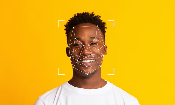 A smiling individual sits against a vibrant yellow background, with facial recognition technology overlay capturing key features. The scene highlights modern identification methods. photo