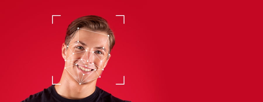 A person smiles while facial recognition technology analyzes their face against a blank red background. This demonstrates the advancements in identification processes in modern society. photo