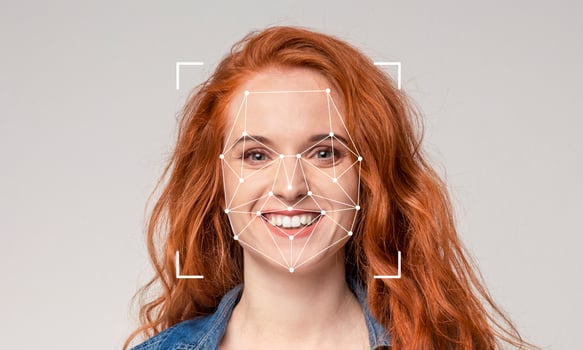 A woman with vibrant red hair is smiling warmly. Her facial features are being analyzed using advanced recognition technology marked with geometric shapes, emphasizing identification. photo