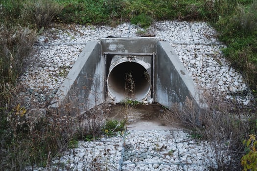 A large pipe is emerging from a concrete structure, protruding prominently and likely serving a significant function in the overall design and utility of the surrounding area photo