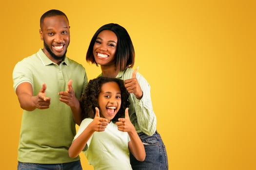 Hey, you. Excited black parents and their daughter pointing fingers at camera, choosing and picking you, standing isolated over yellow studio background, banner photo