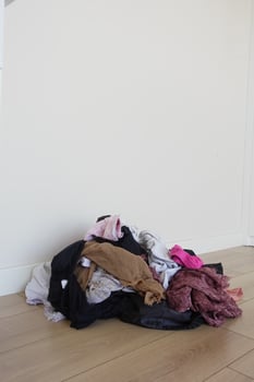 A Tumbling Pile of Unfolded Clothes Scattered on a Wooden Floor Surface photo