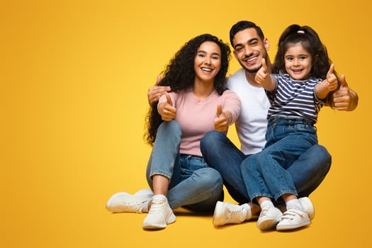 We Recommend. Portrait Of Happy Arab Family Of Three Showing Thumbs Up At Camera, Joyful Middle Eastern Parents And Little Daughter Gesturing Sign Of Approval, Posing On Yellow Background, Copy Space photo