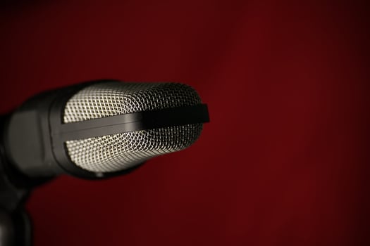 Closeup of a studio microphone against a dark red background photo