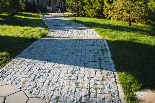 There is a beautiful stone walkway located in a park that is surrounded by lush green grass and tall trees, creating a serene and peaceful atmosphere for visitors to enjoy photo