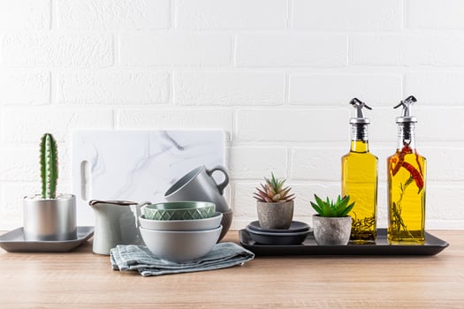 Kitchen Ceramic Cookware Set On Wooden Countertop, Oil In Bottles For Cooking. Plants. Front view. White brick wall. Modern style of kitchen space photo