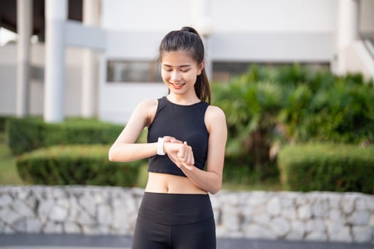 asian woman wearing black sports bra and black leggings checking her smart watch photo