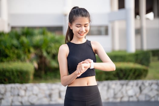 asian woman wearing sports bra and black pants checking her smart watch photo