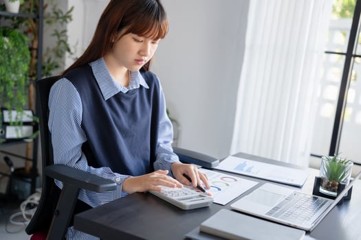 a woman is sitting at a desk with a laptop and a calculator photo