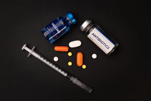 A vaccine antibiotics pills and a syringe lie on a dark surface. health and medical concept photo