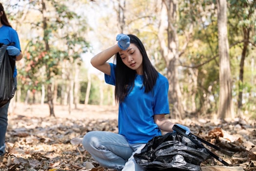 Volunteer taking a break while collecting garbage in a forest, showcasing dedication and environmental awareness photo