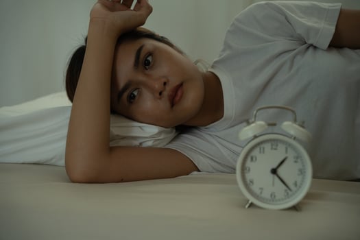 female in bed late trying to sleep suffering insomnia, sleepless or scared in a nightmare, looking sad worried and stressed. Tired and headache or migraine waking up in the middle of the night. photo