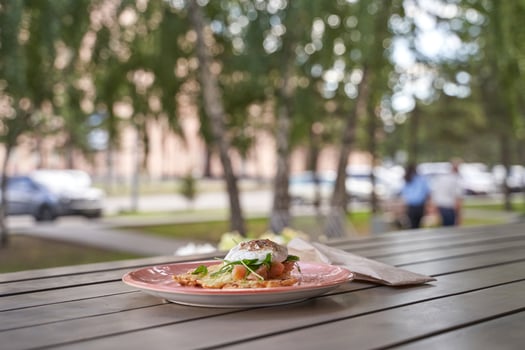 Delicious plate of eggs benedict with fresh arugula on an outdoor table in a sunny park setting. photo