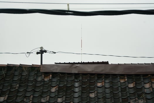 Rooftop With Antenna and Overhead Power Lines on a Cloudy Day photo