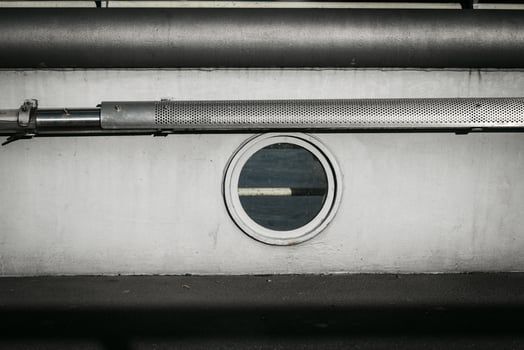Unique industrial design featuring a round window and metal piping in a minimalist interior setting photo