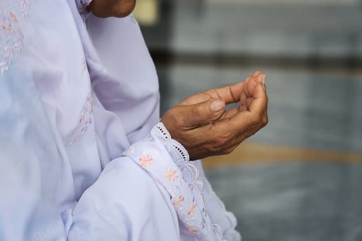 Senior Muslim Woman Praying in Mosque Wearing Mukena photo