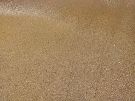 Fine golden sand covering a beach during a sunny day skies, creating a serene and tranquil atmosphere for relaxation photo
