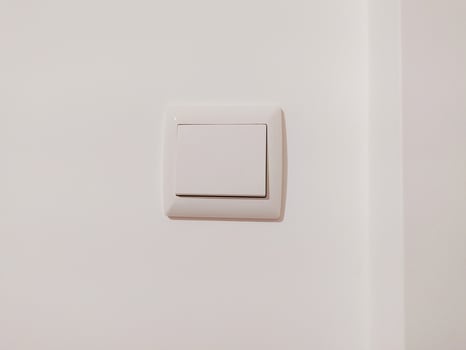 Clean, minimalist image of a single white light switch on a white wall. Perfect for interior design, home improvement, or minimalist lifestyle projects. photo