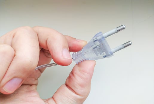 Closeup shot of a hand holding a transparent electrical plug with two prongs. Perfect for illustrating articles on electricity, household appliances, or DIY projects. photo
