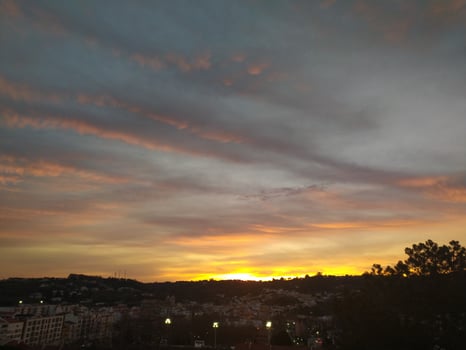 Stunning sunset over a cityscape. Warm golden hues paint the sky, contrasting beautifully with the dark silhouettes of buildings and trees. Ideal for travel, nature, or citythemed projects. photo