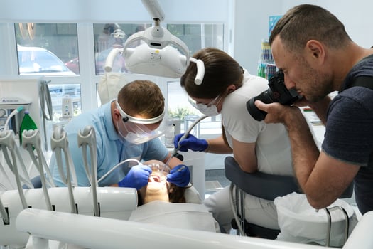 photographer takes pictures of dental treatment process videographer shoots man Dental treatment. Woman on dental examination. Professional equipment in dental clinic photo