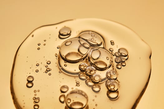 A beautiful drop of gel-like cosmetic serum with bubbles on a golden background. photo