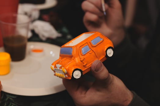 A Creative Painting Activity Featuring a Miniature Model of an Orange Car Design photo