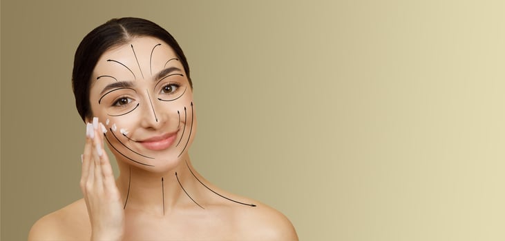 A woman enjoys her pampering skin care routine, carefully applying treatment to her face. The bright, empty backdrop highlights her focus on beauty and self-care. photo