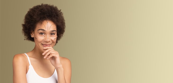 A smiling African American woman with natural beauty is engaging in a skincare routine. She is isolated against a soft, neutral backdrop, showcasing her pampering process with an air of tranquility. photo